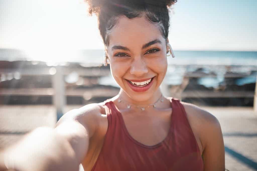 Fitness, black woman and portrait smile for selfie, vlog or profile picture by beach for running ex