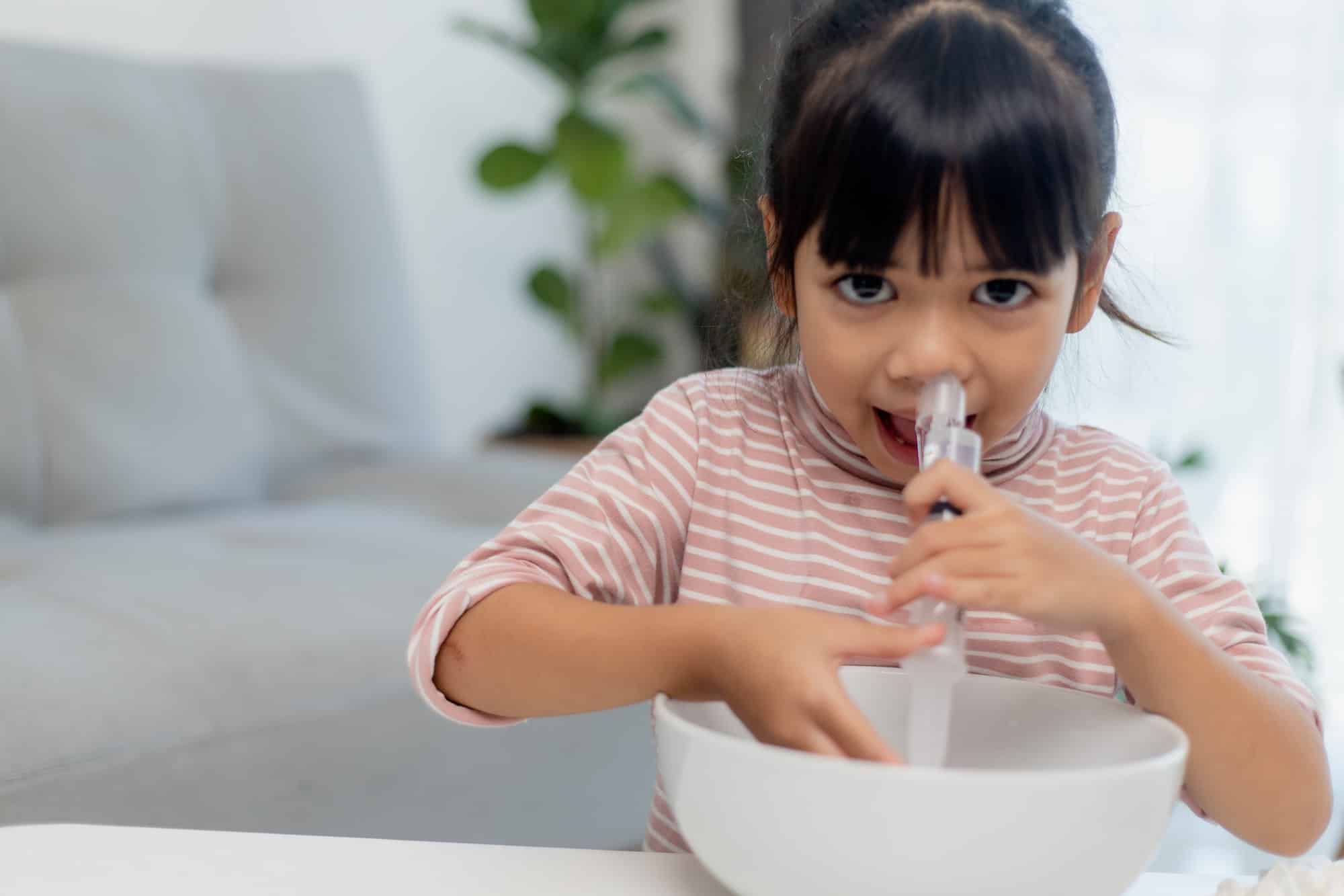 Little asian girl saline nasal wash nose at home.